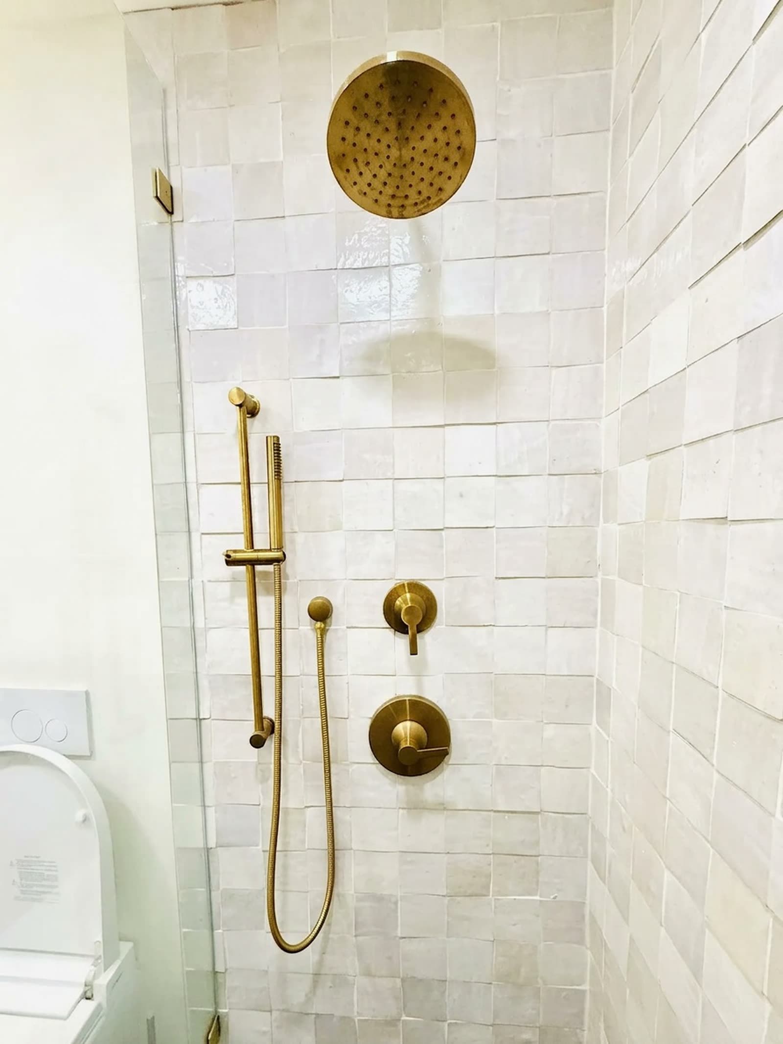A bathroom finished in brass fixtures and hand-set tile.